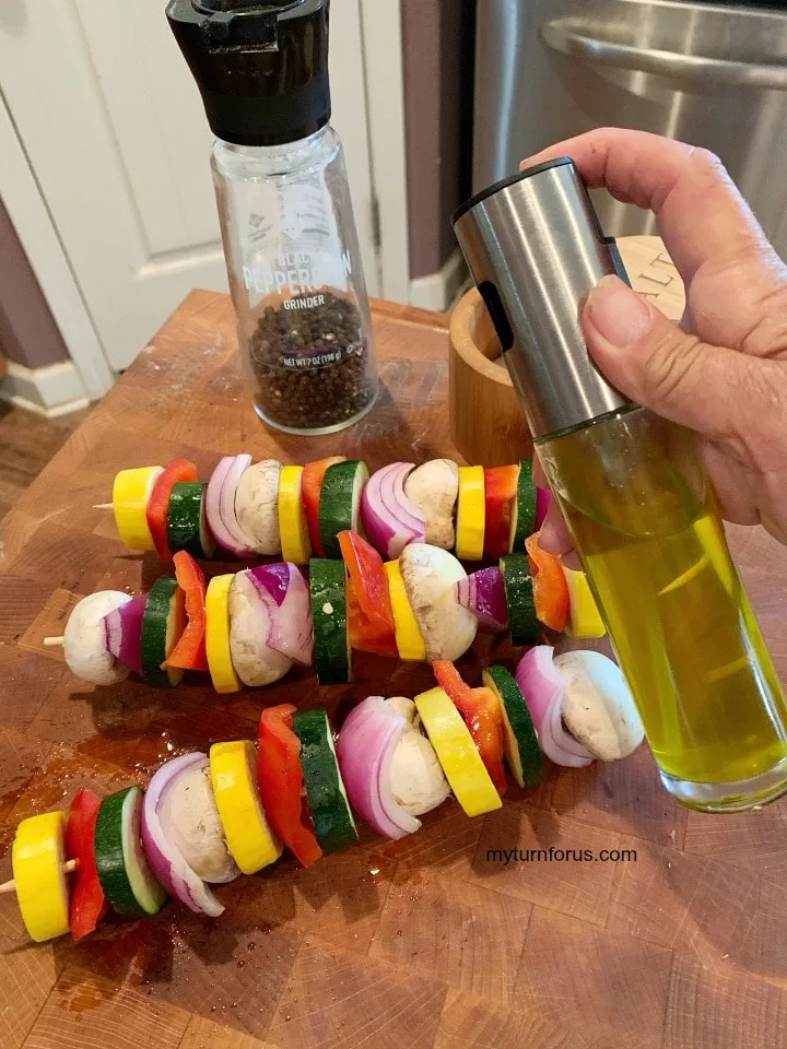 veg kabab, vegetables on a skewer being sprayed with olive oil