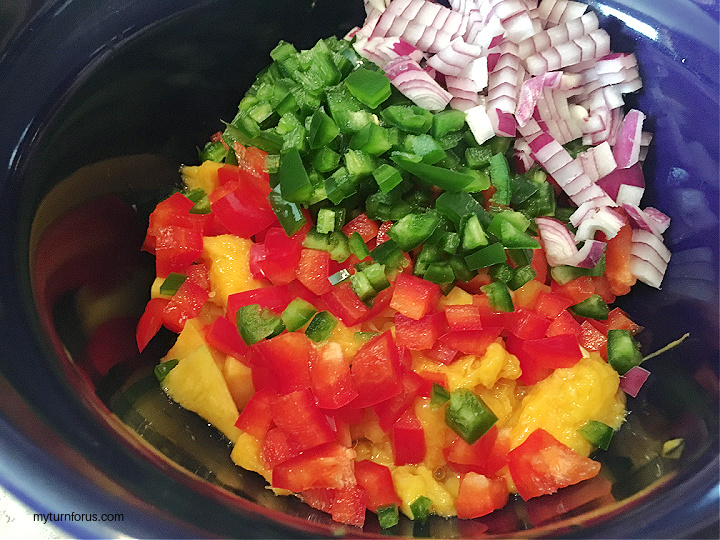 making mango salsa with mangos, peppers, jalapeños and red onion 