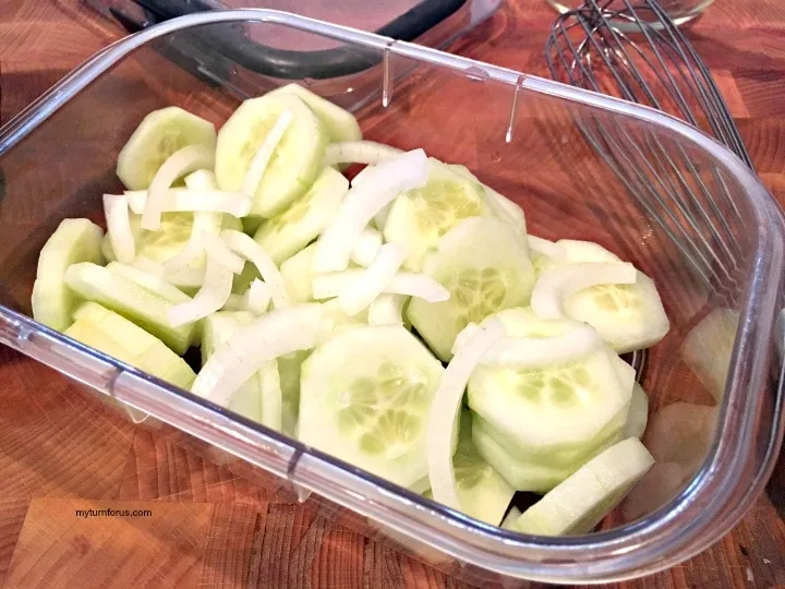 cucumber salad with vinegar, cucumbers with vinegar, sliced cucumbers and onions in a fridge safe dish