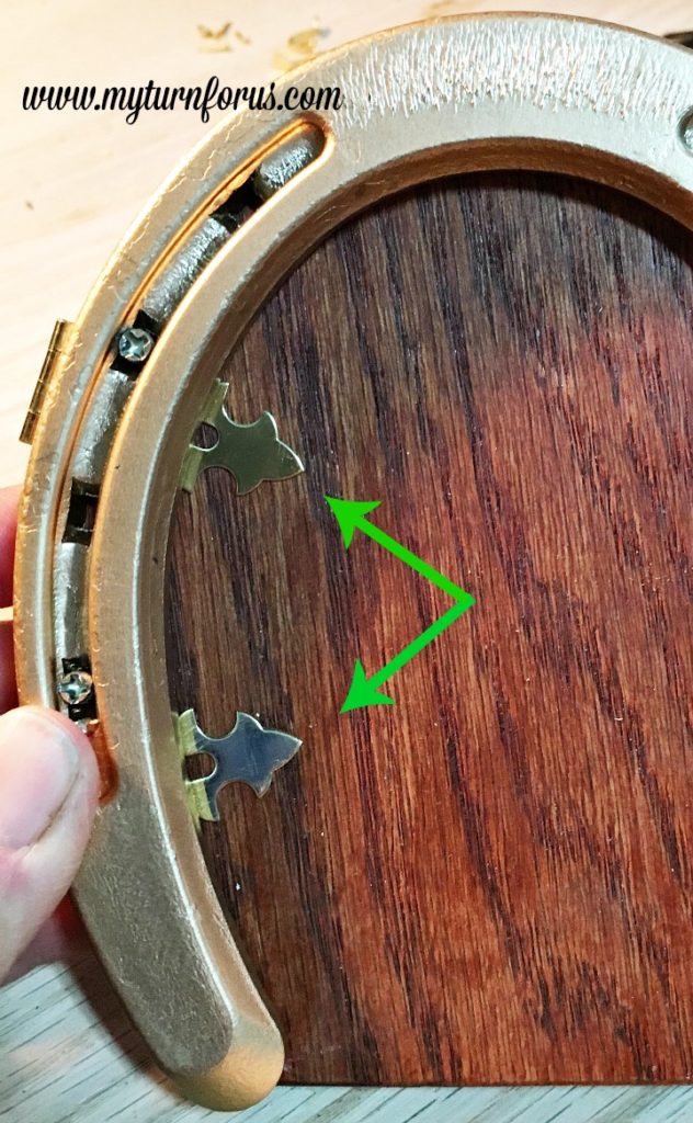Horseshoe Fairy Door for the most magical fairy garden! https://www.myturnforus.com/2016/03/horseshoe-fairy-door.html Close-up showing two decorative hasps positioned along the left side of the wooden fairy door beneath the gold horseshoe.