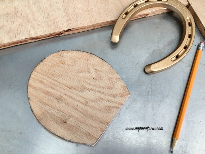 Horseshoe Fairy Door for the most magical fairy garden! https://www.myturnforus.com/2016/03/horseshoe-fairy-door.html Cut plywood fairy door beside a gold-painted horseshoe and pencil.