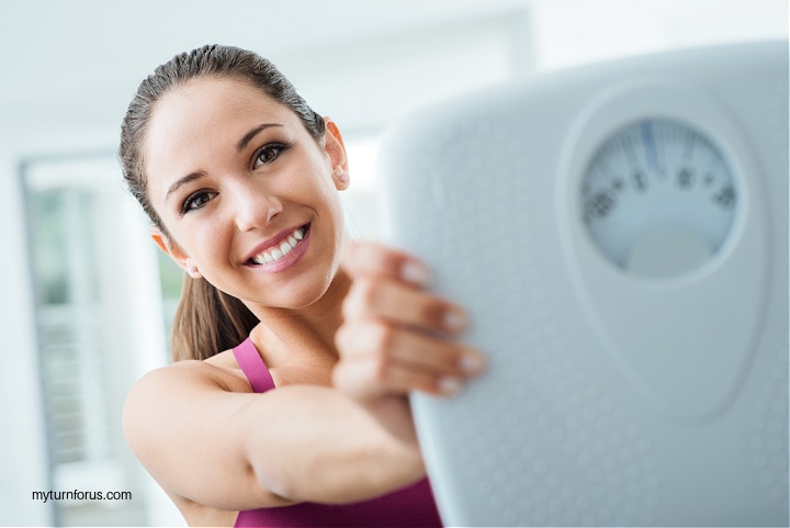 beat that roadblock of not losing weight, women happily holding weight scale