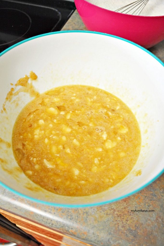 Mashed bananas mixed with wet ingredients in a bowl for homemade banana bread batter.