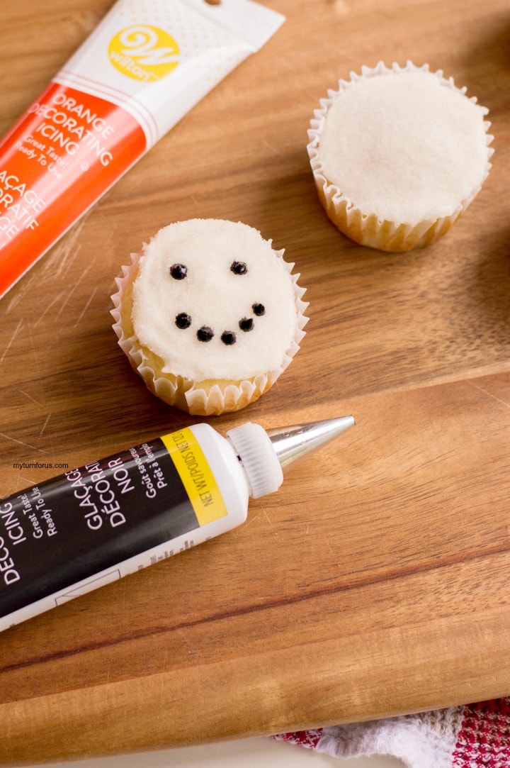 Making the Snowman Face Cupcakes with black and orange icing