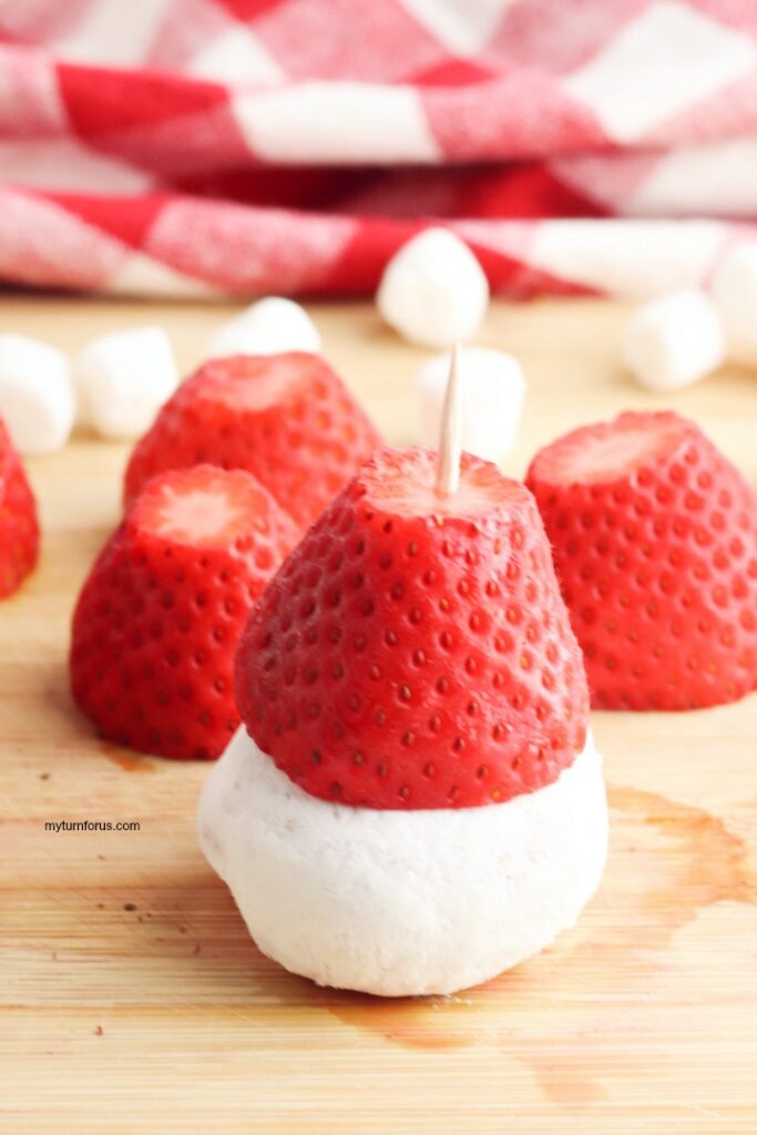 Toothpick in strawberry and donut Toothpick inserted through a strawberry into a mini powdered donut to hold the Santa hat together.