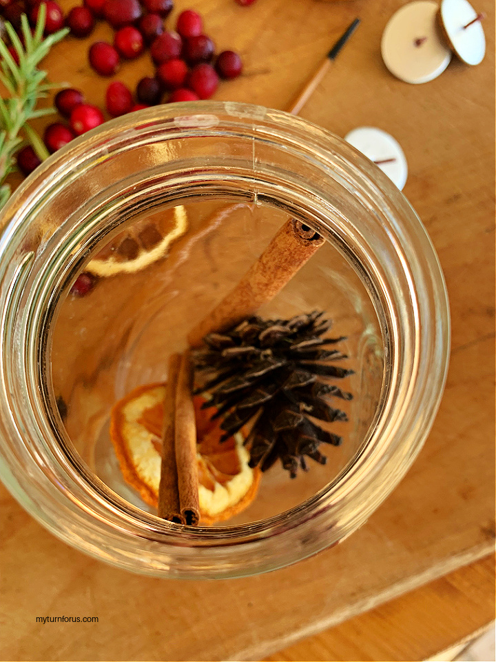 Jar with pine cones, cinnamon sticks and orange slices