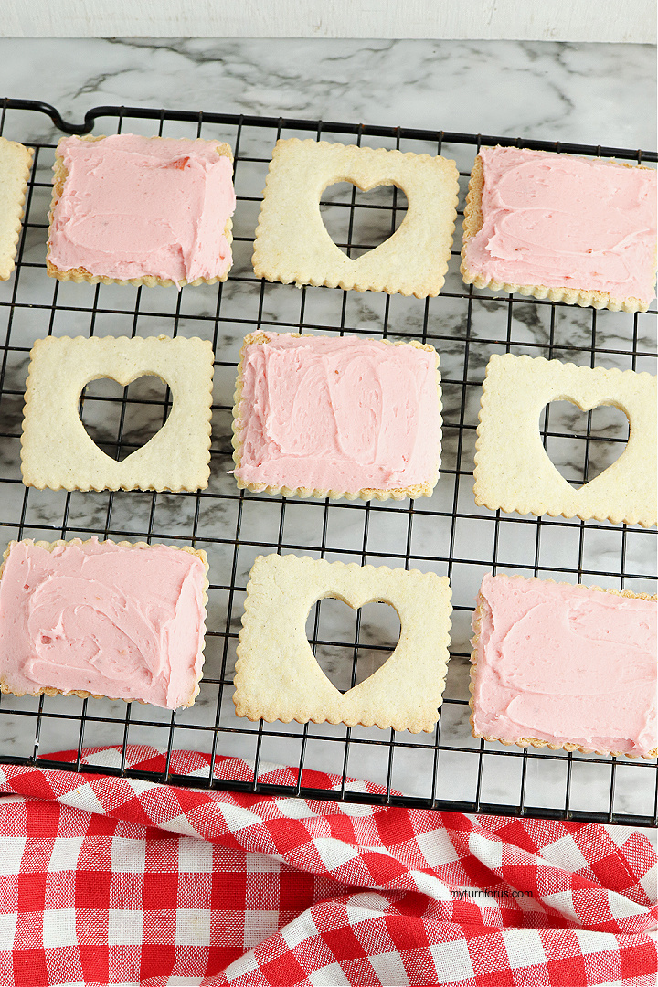 spreading the jam buttercream on the heart cookies