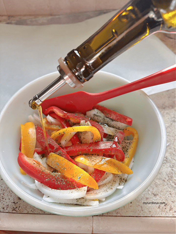 adding olive oil to the peppers and onions